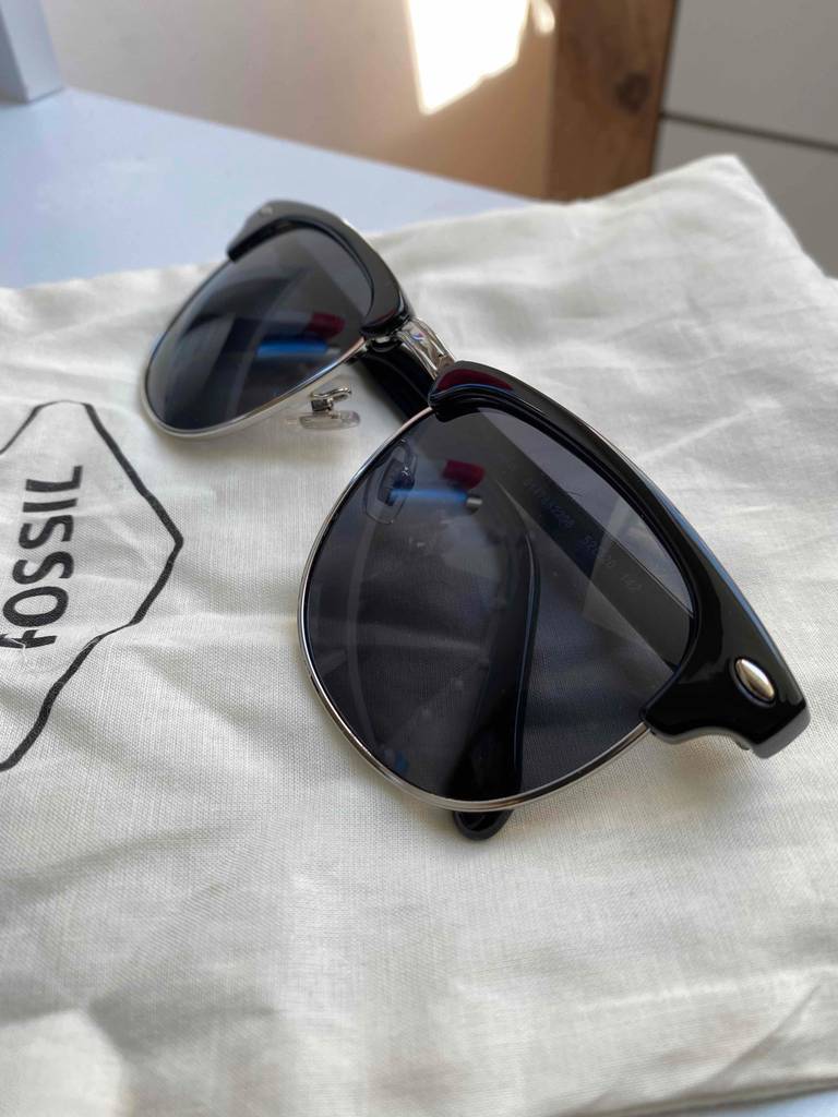 Eine getestete Herren-Sonnenbrille liegt mit zusammengeklappt auf einer weißen Stofftasche.