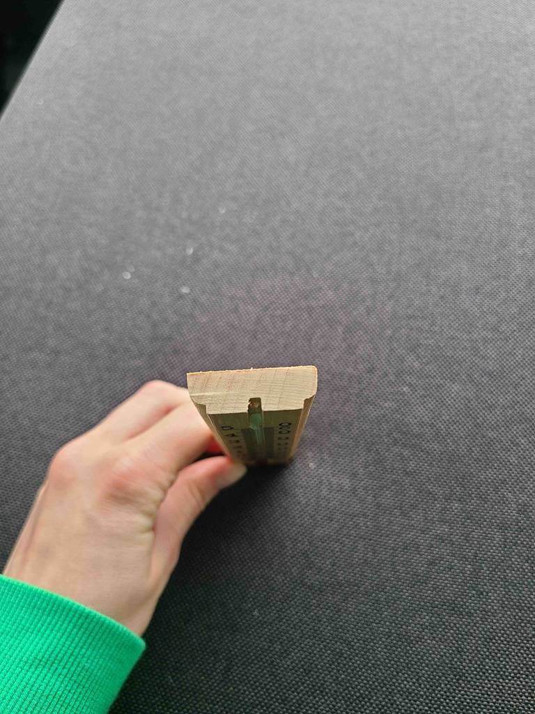 Blick von oben auf ein Thermometer analog im Test, das von einer Hand gehalten wird.