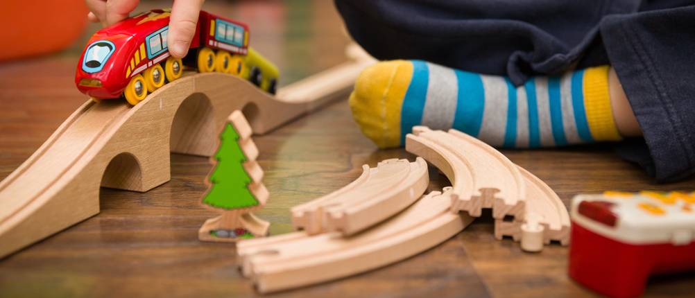 Holzeisenbahn im Test: Ein Kind, das mit einer Kindereisenbahn spielt.