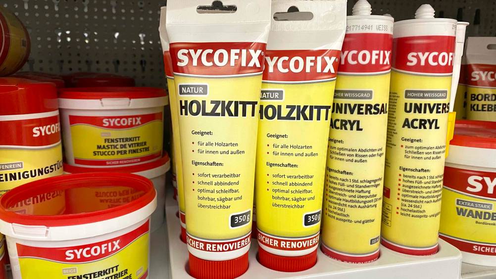 Im Test: Meherere Tuben des Holzkitts nebeneinander mit anderen Produkten in einem Regal.
