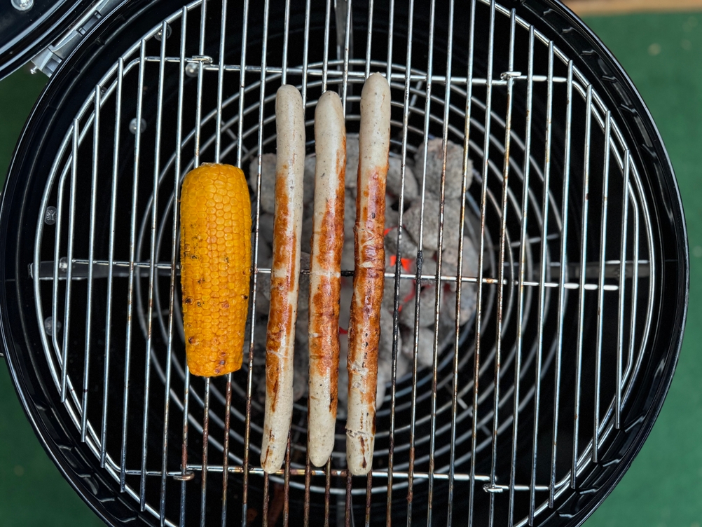 Würste und Maiskolben auf dem getesteten Holzkohlegrill von Rösle.