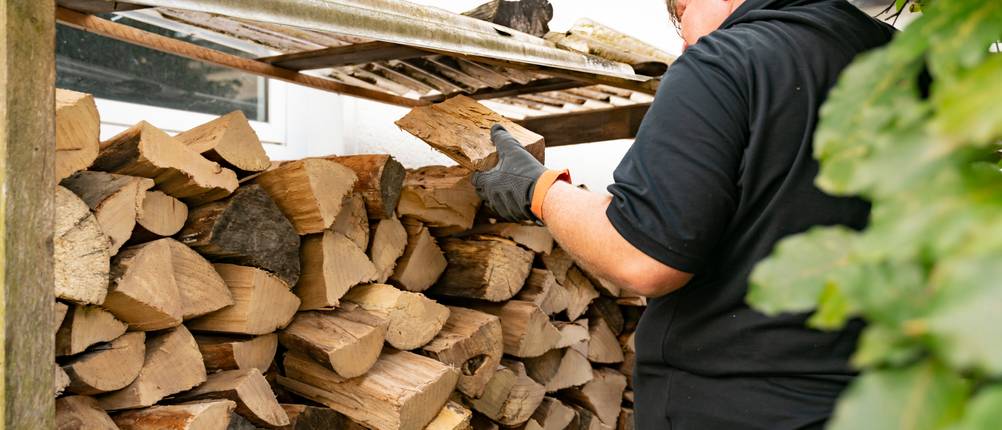 Holzlege-Test: Mann schichtet Holzscheite