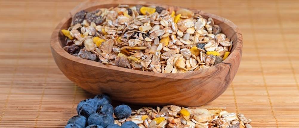Holzschale getestet: Eine ovale Holzschale ist gefüllt mit Müsli. Davor liegen Blaubeeren und Müsliflocken.