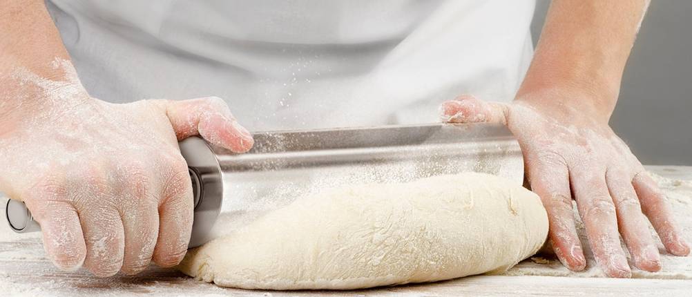 Nudelholz-Test: Ein Bäcker rollt mit einem Edelstahl-Nudelholz Teig aus. 