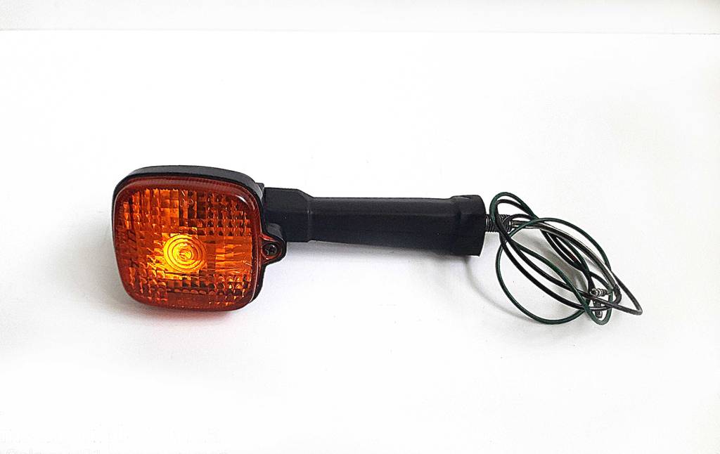 Ein getesteter Motorrad-Blinker liegt quer auf einer weißen Fläche.