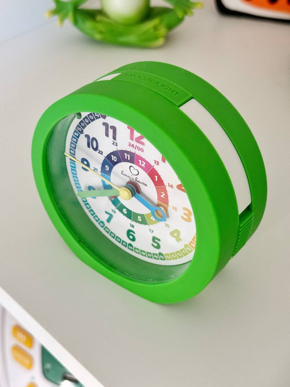 Kinderwecker im Test: Ein grüner Wecker mit buntem Ziffernblatt von schräg oben betrachtet.