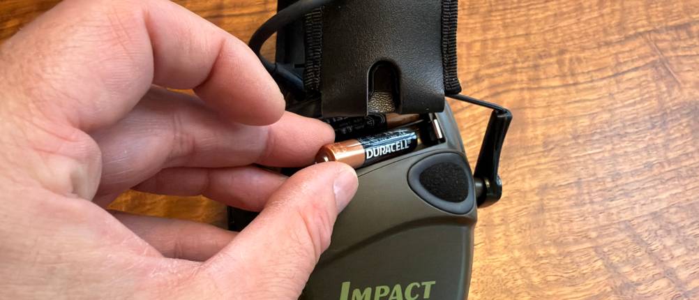 Eine Hand legt eine Batterie in ein Fach im Honeywell Howard Leight Impact Sport.
