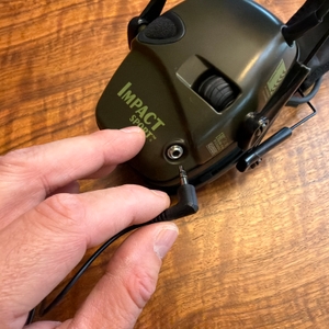 Eine Hand steckt ein Kabel in den Honeywell Howard Leight Impact Sport.