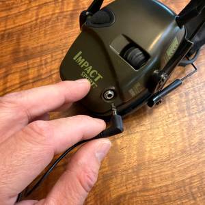 Eine Hand steckt ein Kabel in den Honeywell Howard Leight Impact Sport.