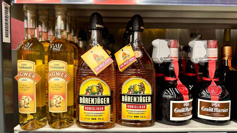 Mehrere Flaschen des Honiglikörs im Test neben anderen Produkten in einem Verkaufsregal.