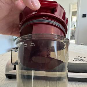 Eine Hand öffnet den Behälter des Hoover Ultra Vortex