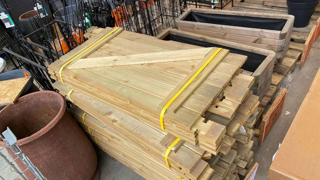 Ansicht von oben auf die Verpackung mit den Komponenten eines Sandkastens aus Holz im Test, der sich im Baumarkt befindet.