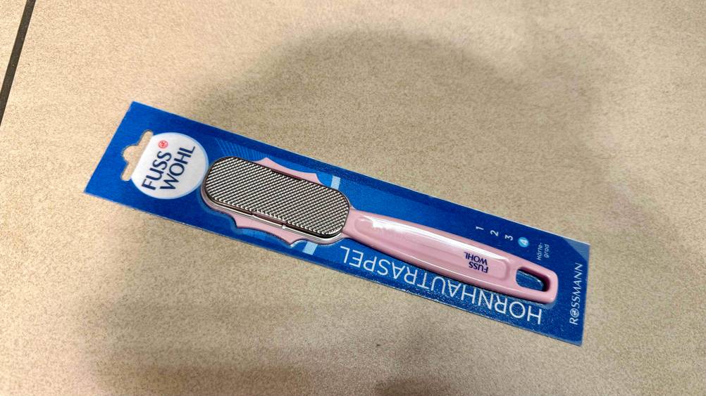 Ein Hornhautraspel im Test horizontal auf einem beigen Boden liegend.