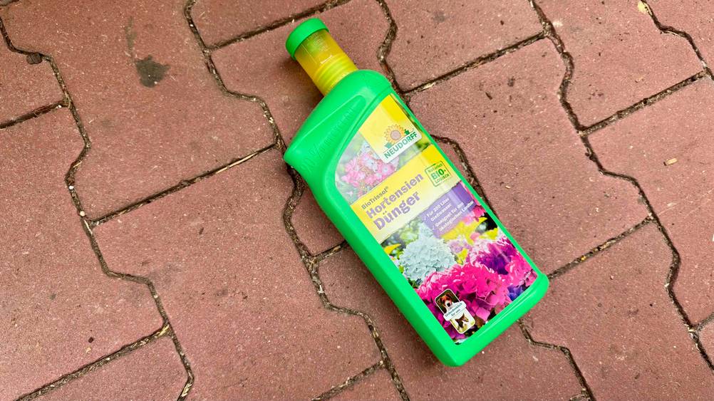 Auf einem Steinboden liegt eine Flasche des Hortensiendünger im Test.