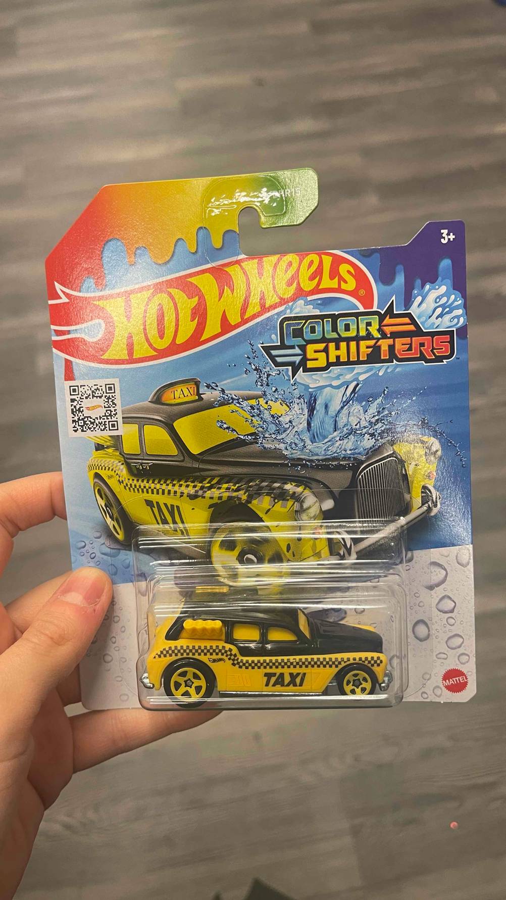 Das für Kinder ab drei Jahren geeignete und getestete Hot-Wheels-Auto Spielzeug in der Verpackung wird von einer Hand gehalten.