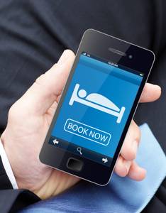 Hotels im Test: Ein Mann hält ein Smartphone in der Hand und bucht mit diesem eine Unterkunft.