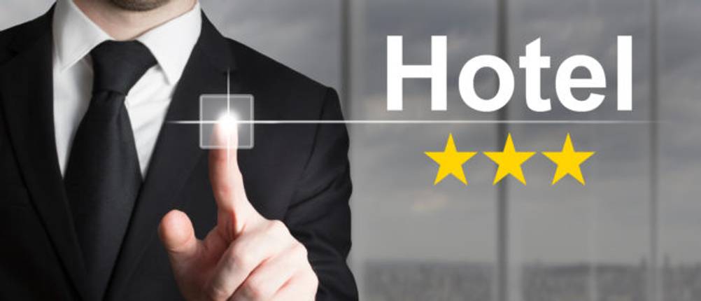 Hotels im Test: Ein Mann im Anzug tippt auf eine Grafik mit der Aufschrift Hotel, unter der sich drei goldene Sterne befinden.