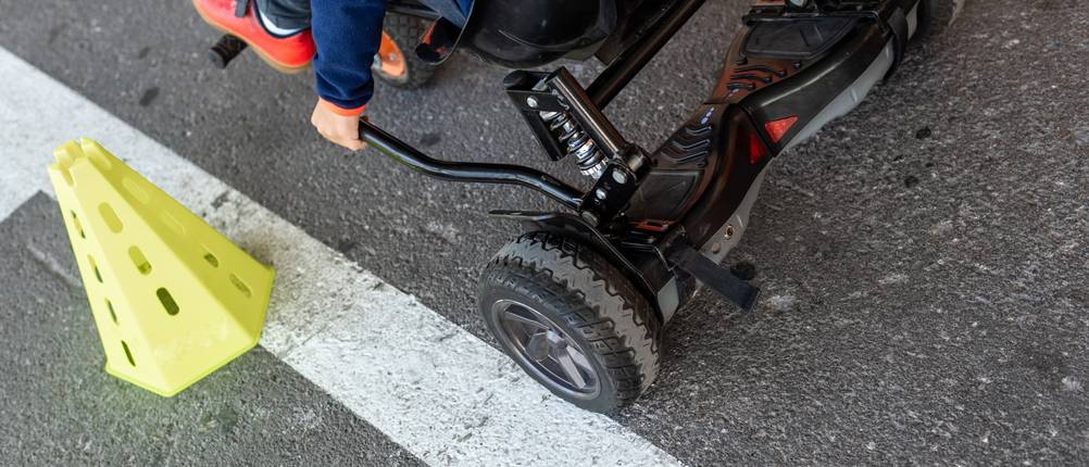 Hoverboard-Test: Person, die auf einem Hoverboard-Kart sitzt, auf asphaltiertem Untergrund
