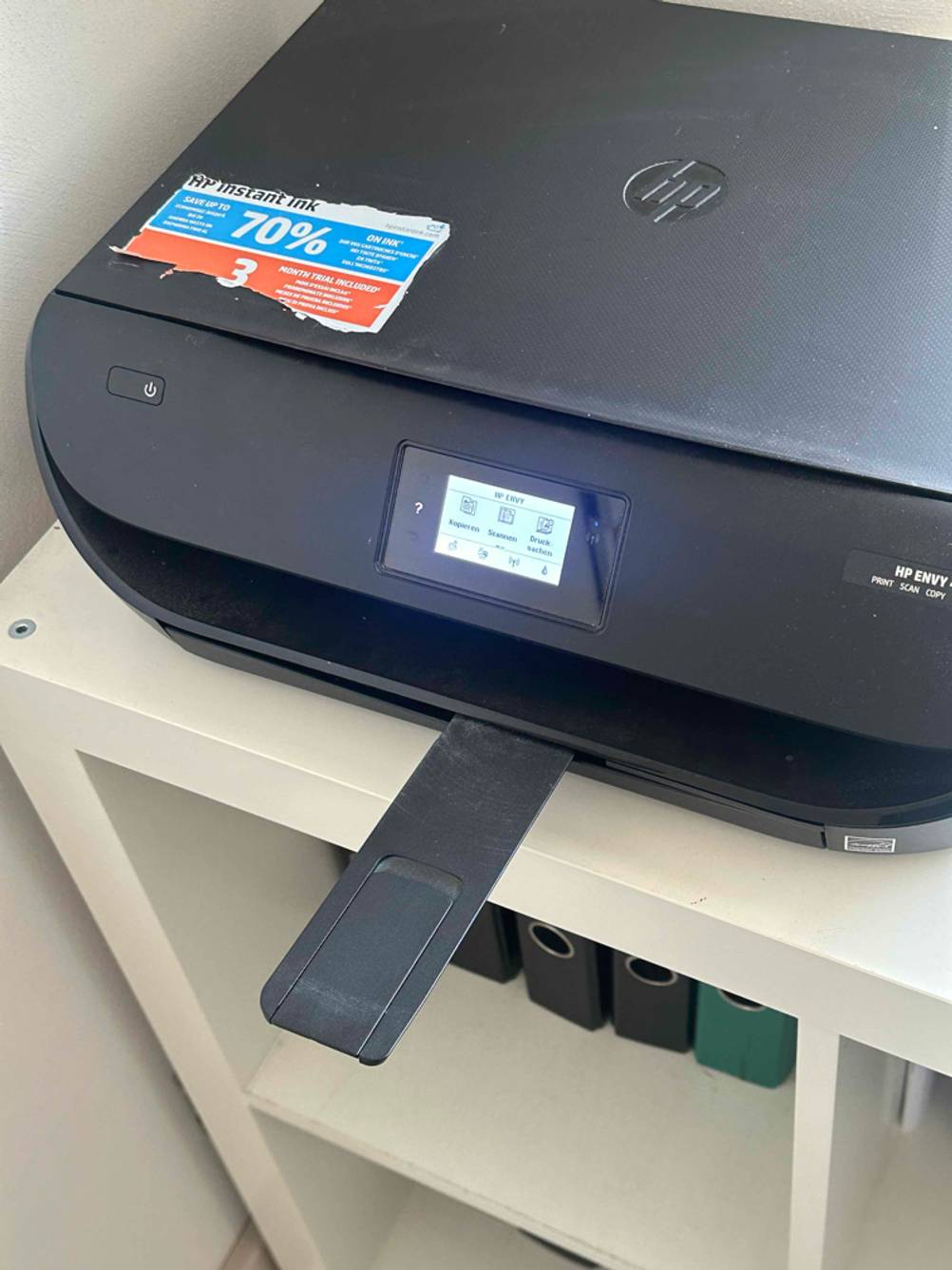 Ein getesteter Bluetooth-Drucker der Marke HP steht eingeschaltet mit herausgezogener Papierausgabe-Schiene auf einem weißen Regal.