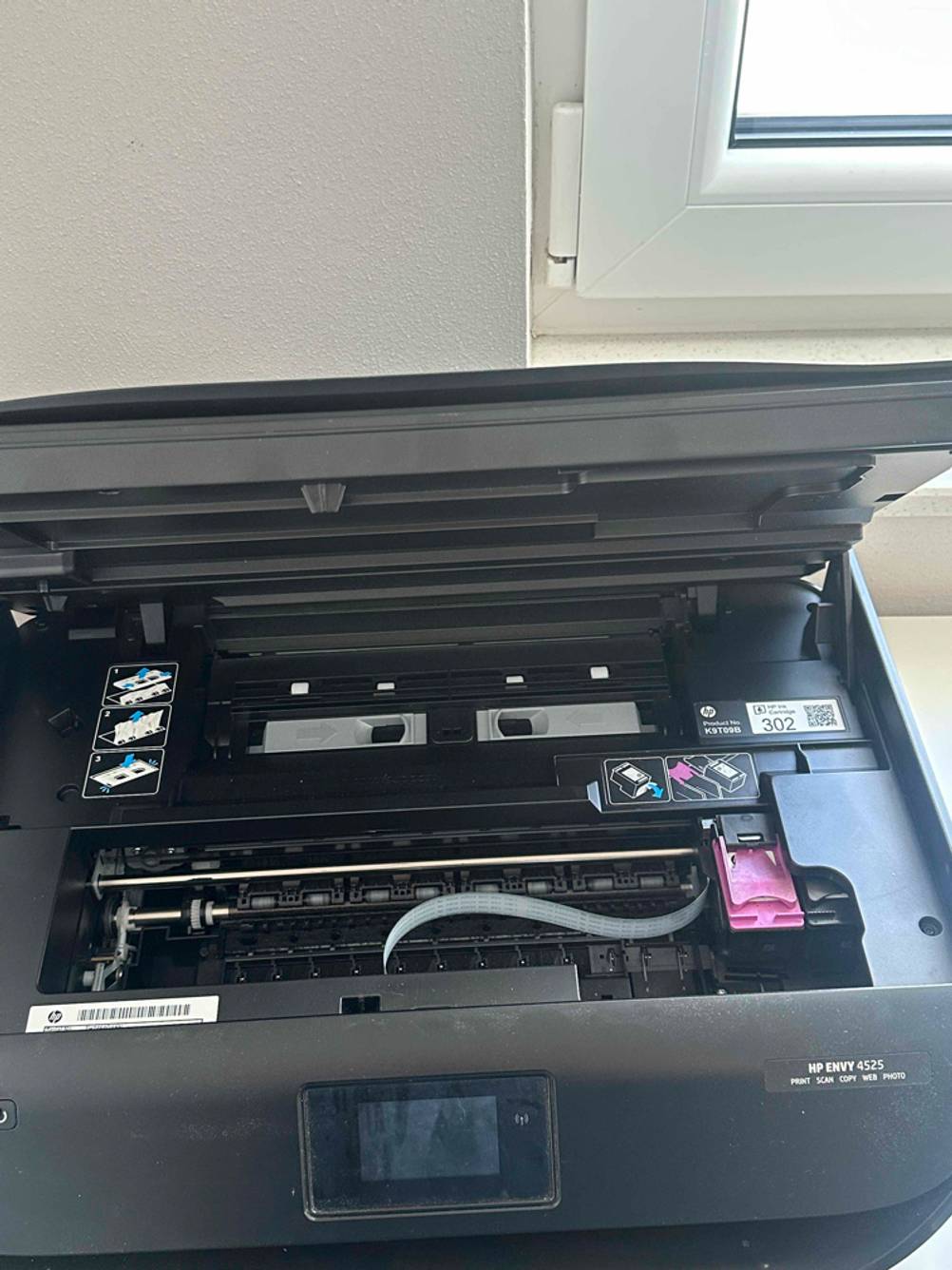 Getestet: Ein Bluetooth-Drucker in Schwarz steht geöffnet, mit Blick auf die Druckschiene, vor einem weißen Fensterrahmen.