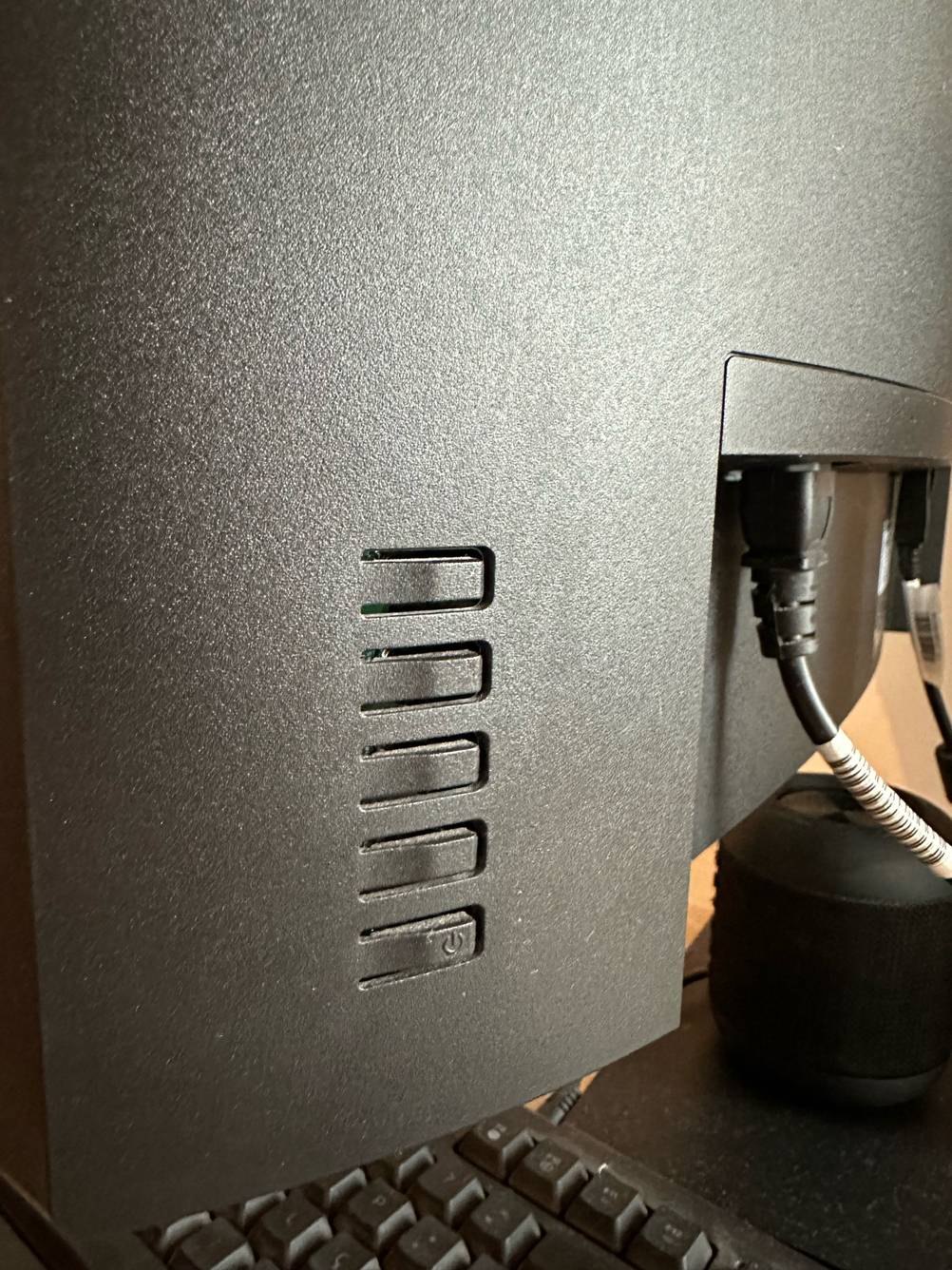 Curved Monitor im Test: Ansicht des Anschlusses für das Stromkabel sowie Powerknopf auf der Rückseite eines Geräts.