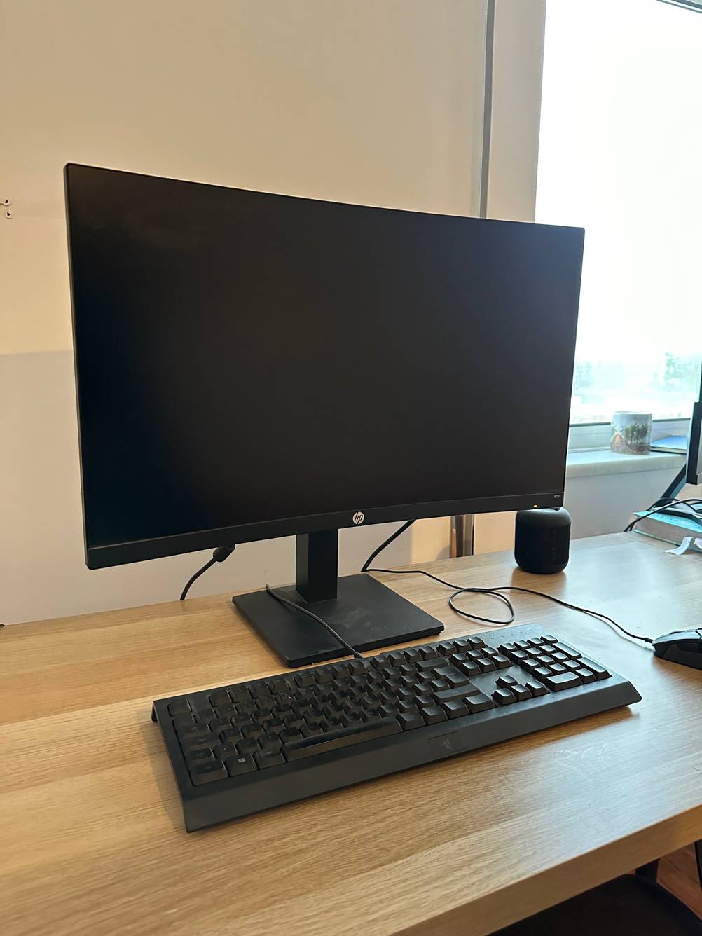 Ein ausgeschalteter getesteter Curved Monitor steht hinter einer Tastatur auf einem Schreibtisch.