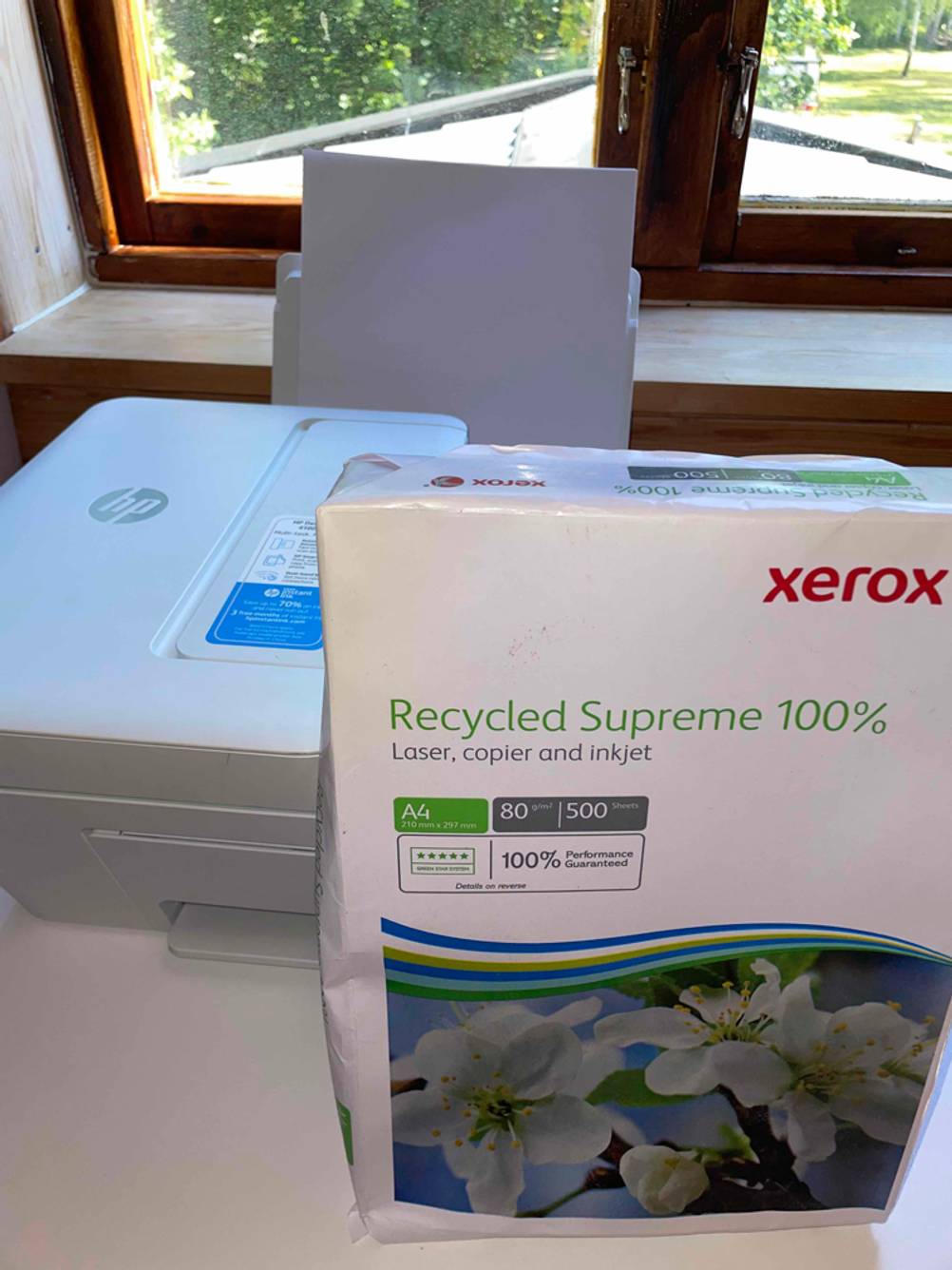 Ein getesteter HP Drucker steht hinter einem Pack Papier.