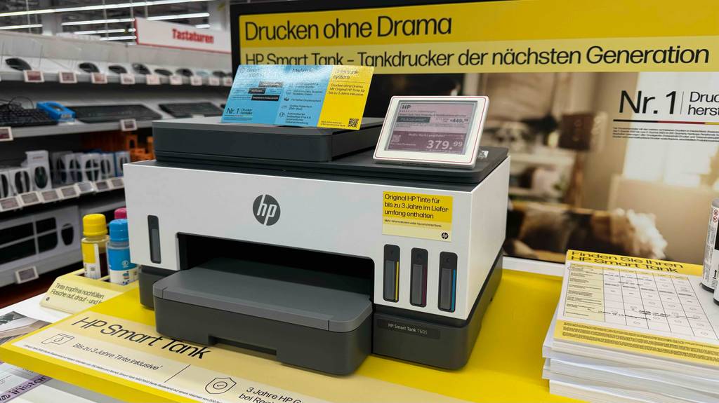 Gesamtansicht von vorn eines Druckers mit Tank im Test: Auf dem HP-Modell befinden sich Produktangaben sowie ein Preisschild.