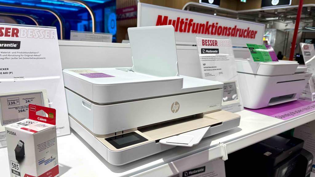 Blick von schräg vorne auf einen HP-Envy-Drucker, der zum testen auf einem Regal steht.