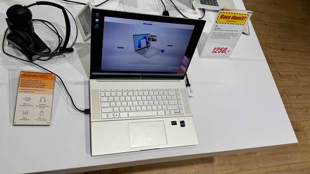 Ein geöffnetes HP-Envy-Laptop im Test von oben auf einer hellen Fläche stehend, daneben ein Preisschild.