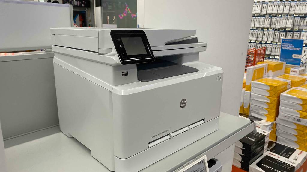 Getesteter HP Laser-Multifunktionsdrucker von schräg vorn betrachtet steht auf weißem Tisch.