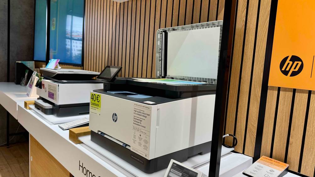 Ein getesteter HP-Laserdrucker auf einem Verkaufsregal neben anderen Produkten.