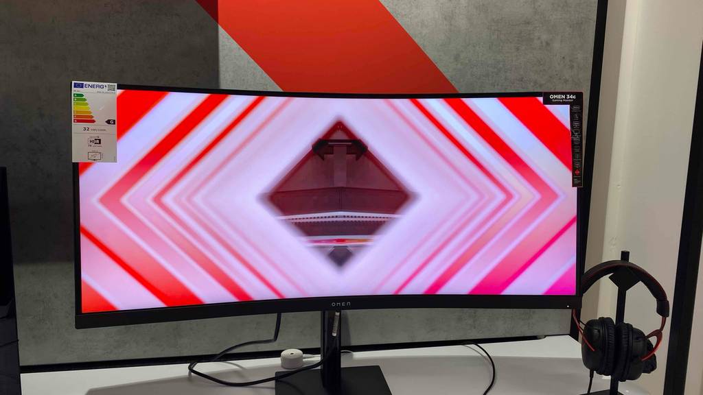 Im Test: Ein 34-Zoll-Monitor angeschaltet von vorne, daneben ein Kopfhörer.