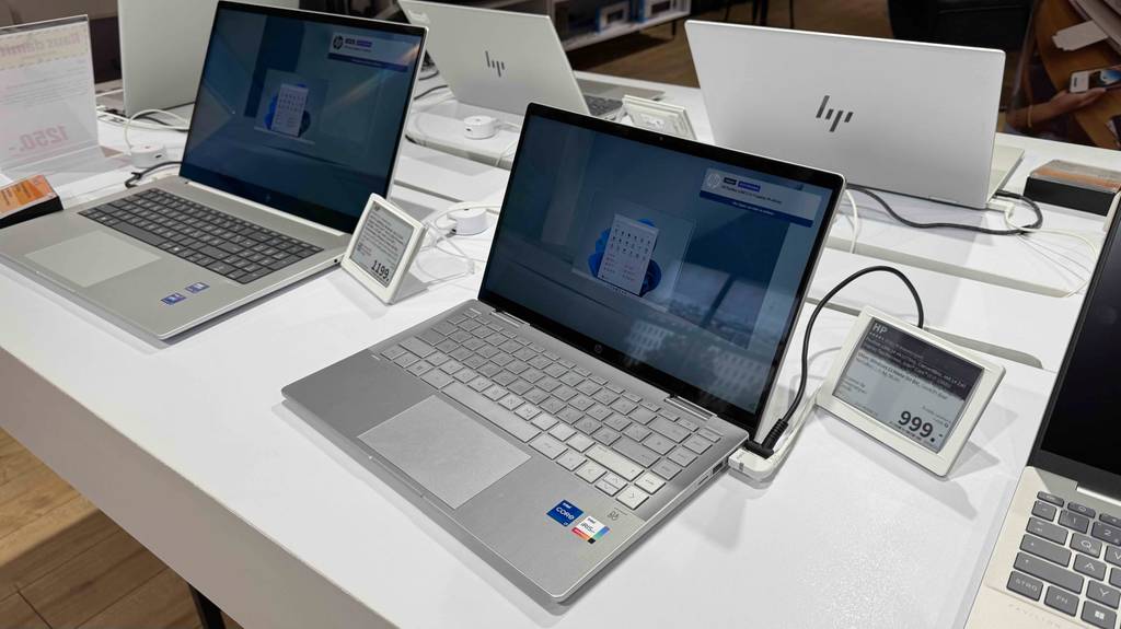 Ein eingeschalteter HP Pavilion PC steht zum testen zwischen anderen Geräten auf einem weißen Tisch.