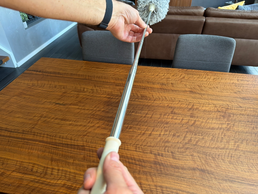 Eine Hand verlängert den Htly-SPR-Spinnwebenbesen.