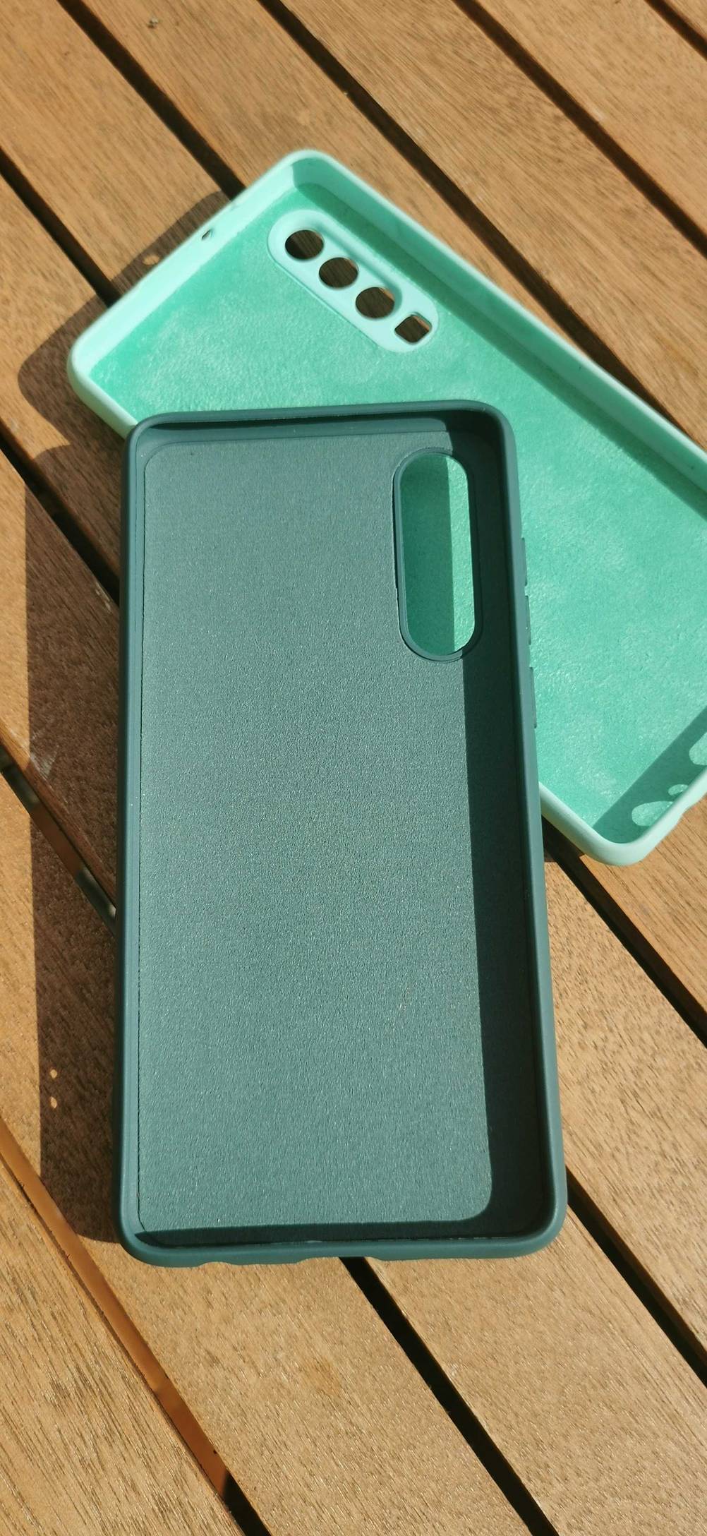 Zwei der getestesteten Huawei-p30-Hüllen in unterschiedlichen Farben leicht übereinander auf einer Holzfläche.