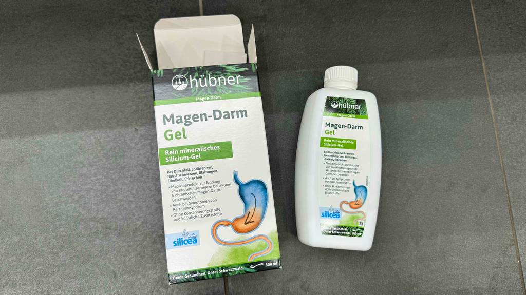 Eine Flasche getesteter Darmreiniger liegt neben der Originalverpackung auf einem Fliesenboden.