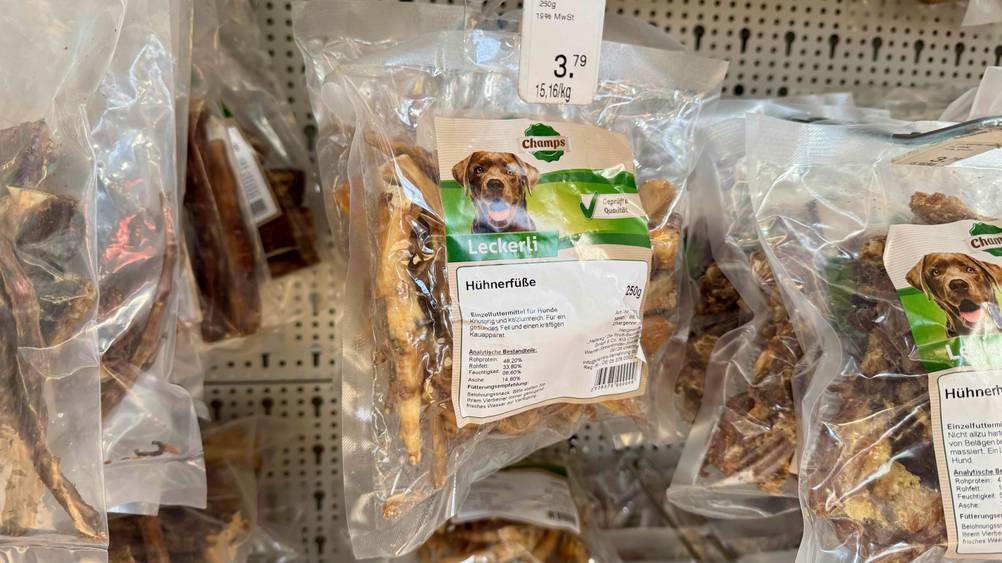 Mehrere Packungen der Hühnerfüße im Test hängen in einem Verkaufsregal neben anderen Produkten.