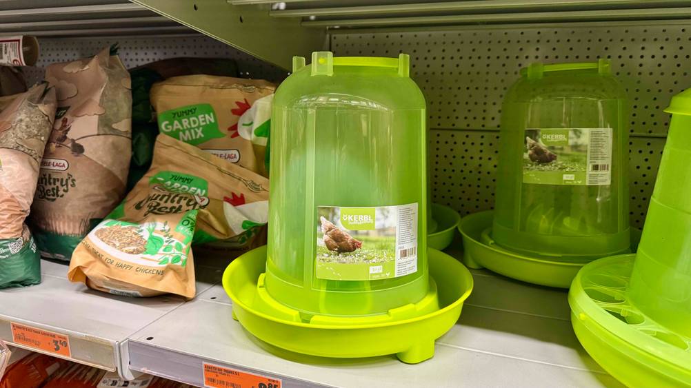 Eine grüne getestete Hühnertränke steht neben anderen in einem Regal.