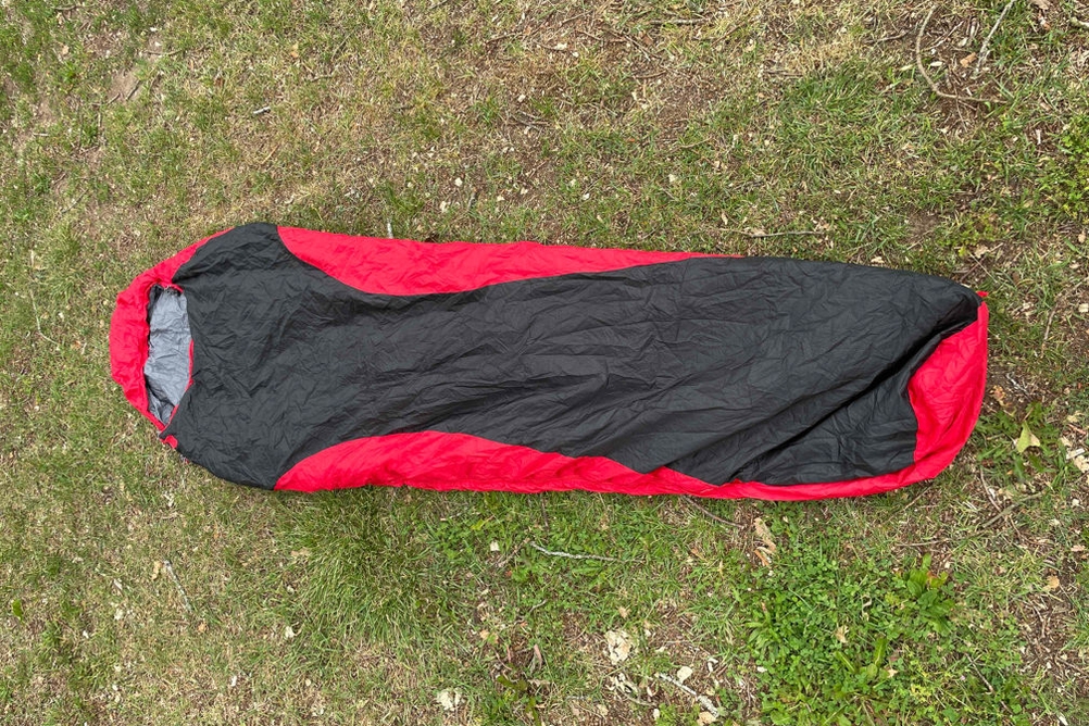 Hüttenschlafsack in Rot-Schwarz auf einer Wiese ausgebreitet