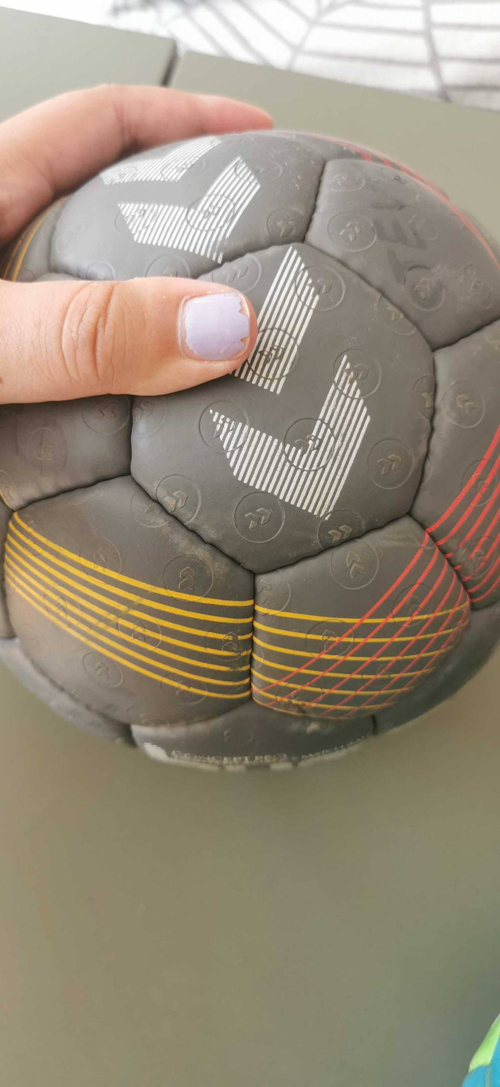 Nahaufnahme des Musters eines getesteten Handballs den eine Hand hält.