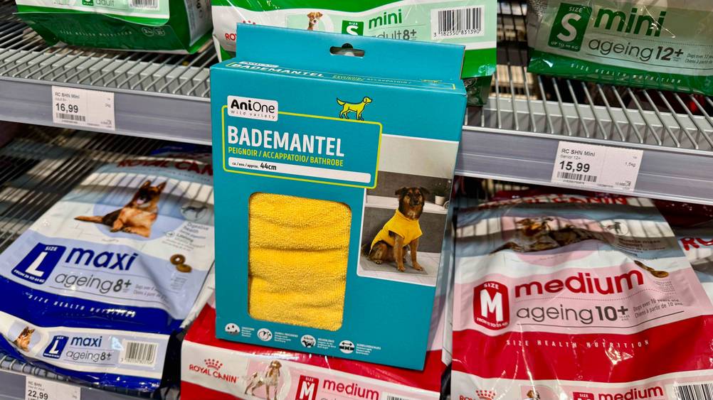 Hundebademantel getestet: Ein gelber Mantel in der Originalverpackung steht auf Hundefutter vor einem Regal mit Preisangaben.
