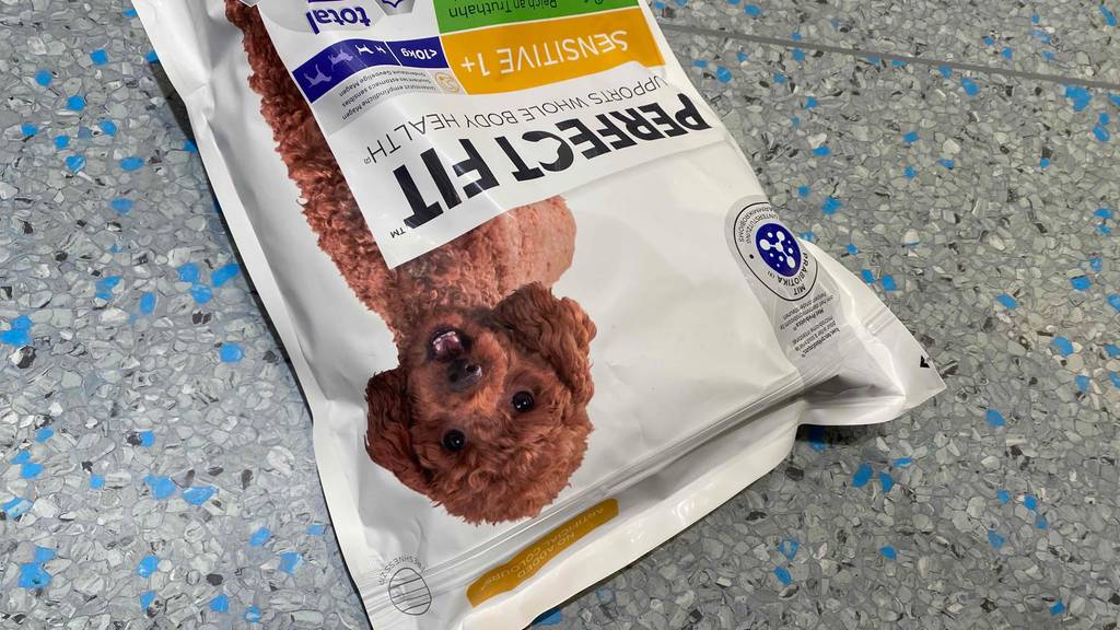 Auf dem Boden befindet sich eine Packung mit getestetem Hundefutter.