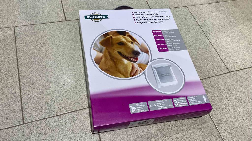 Auf dem Boden liegt eine getestete Hundeklappe in einer Kunststoffverpackung.