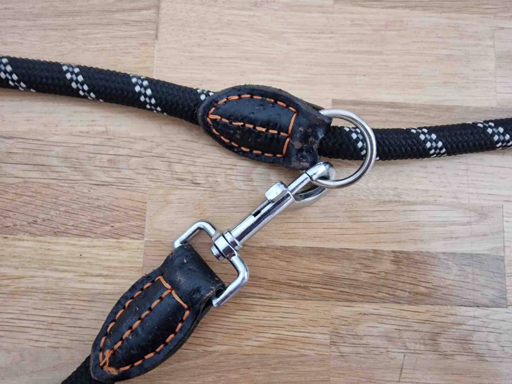 Hundeleine-Test: Nahaufnahme des Metall-Karabiners inklusive Metall-Ring einer schwarz-weiß gestreiften Seil-Leine mit Lederverstärkungen.