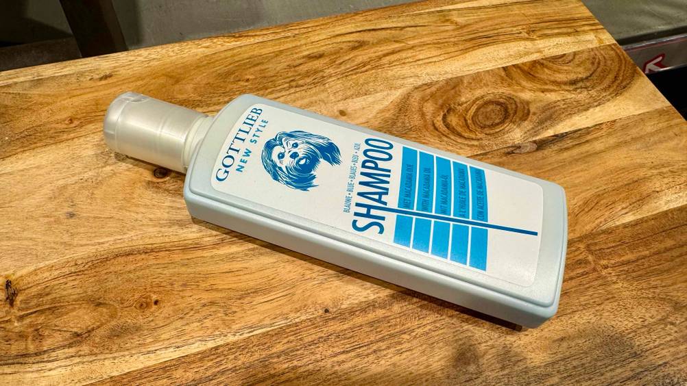 Hundeshampoo (weißes Fell) im Test: Eine Flasche leicht horizontal auf einem Holzbrett.