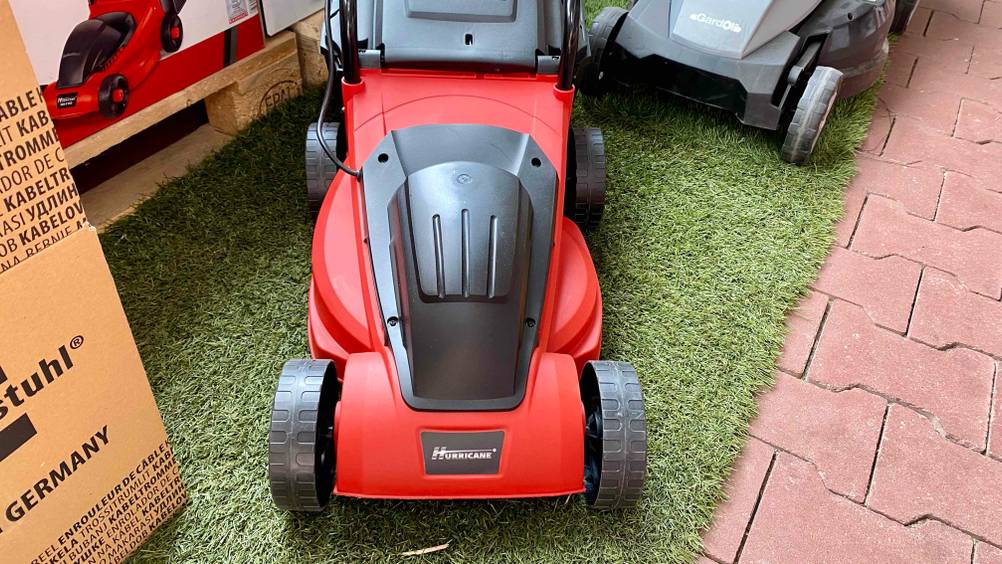 Im Test: Nahaufnahme des Motors und Logos von vorne eines Rasenmähers auf einem Kunstrasen.