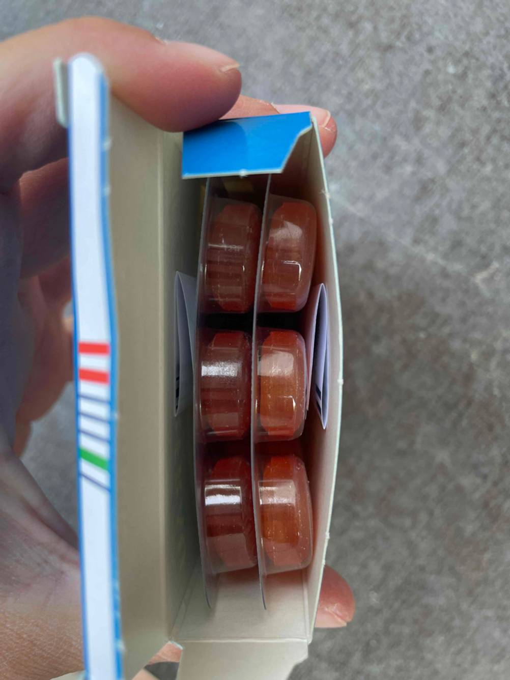 Eine geöffnete Packung der getesteten Hustenbonbons von oben von einer Hand gehalten, im Inneren zwei Tabelettenblister.