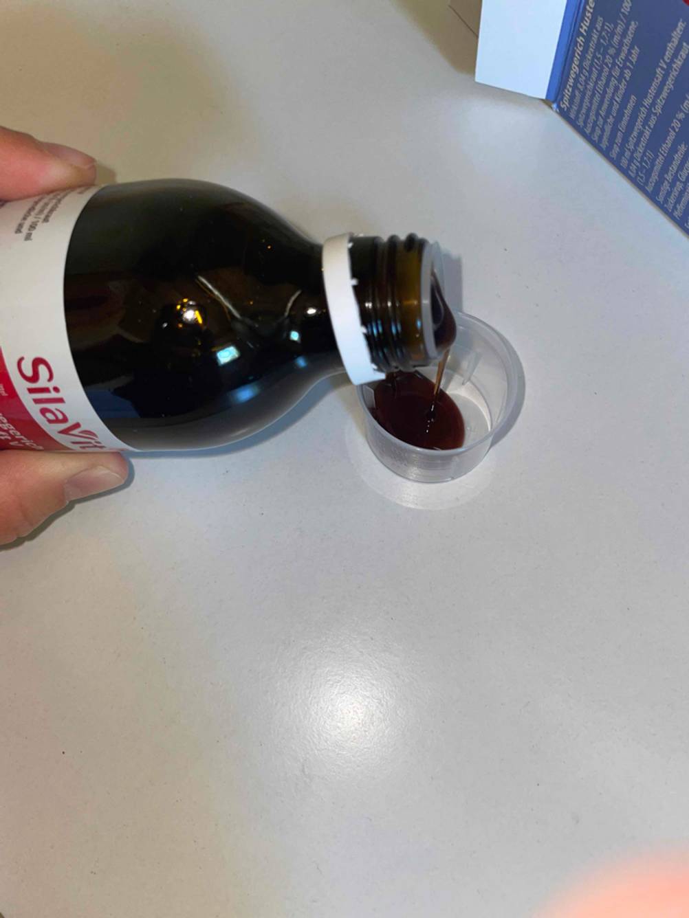 Getesteter Hustensaft wird in die Dosierhilfe eingegossen. 