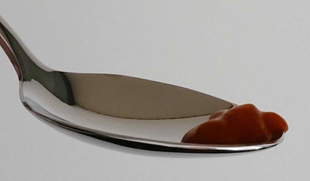 Chili-Soßen-Test: Auf einem Teelöffel befindet sich eine dunkelrote Paste.